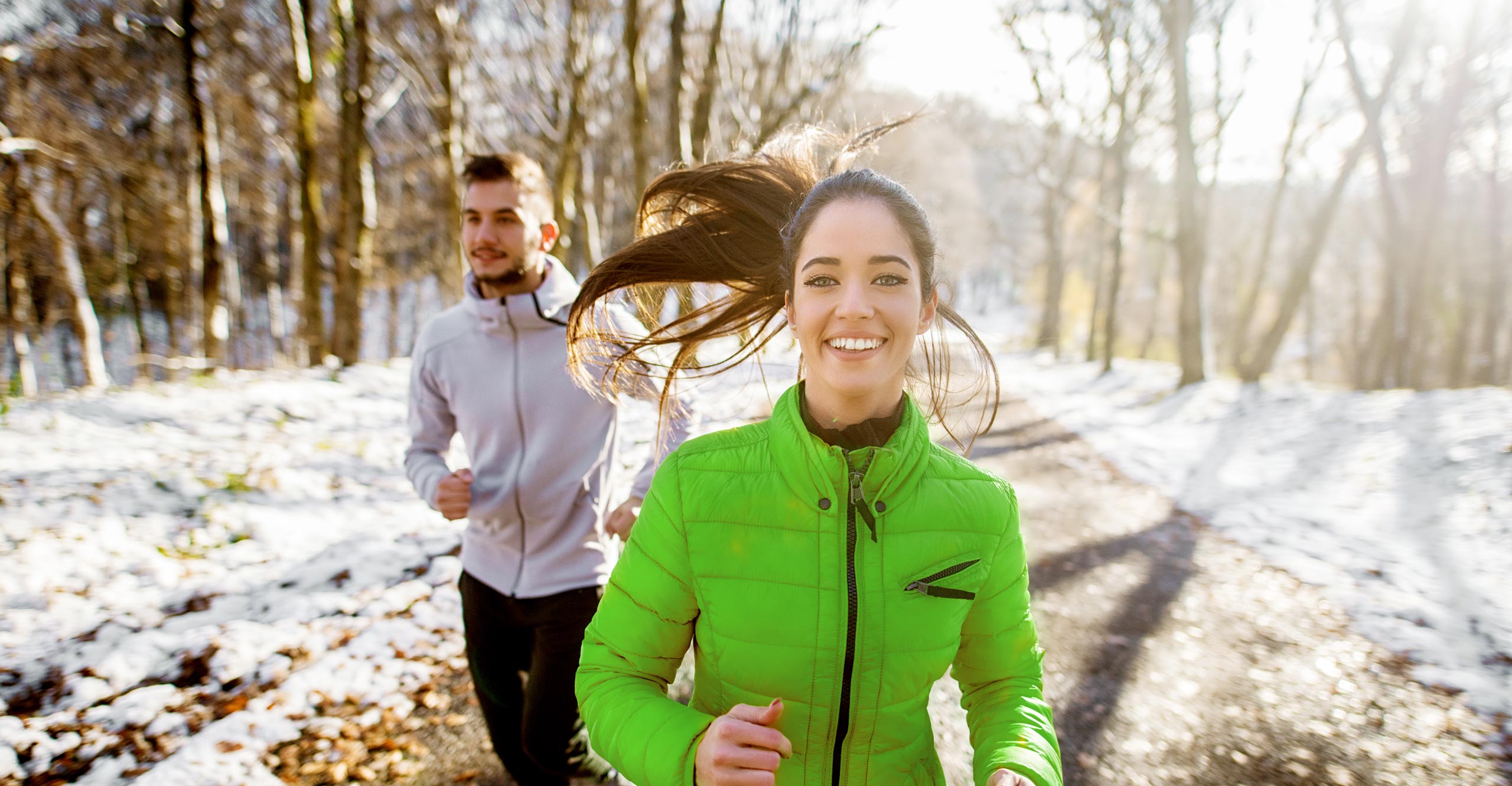 young couple running sporty in winter forest