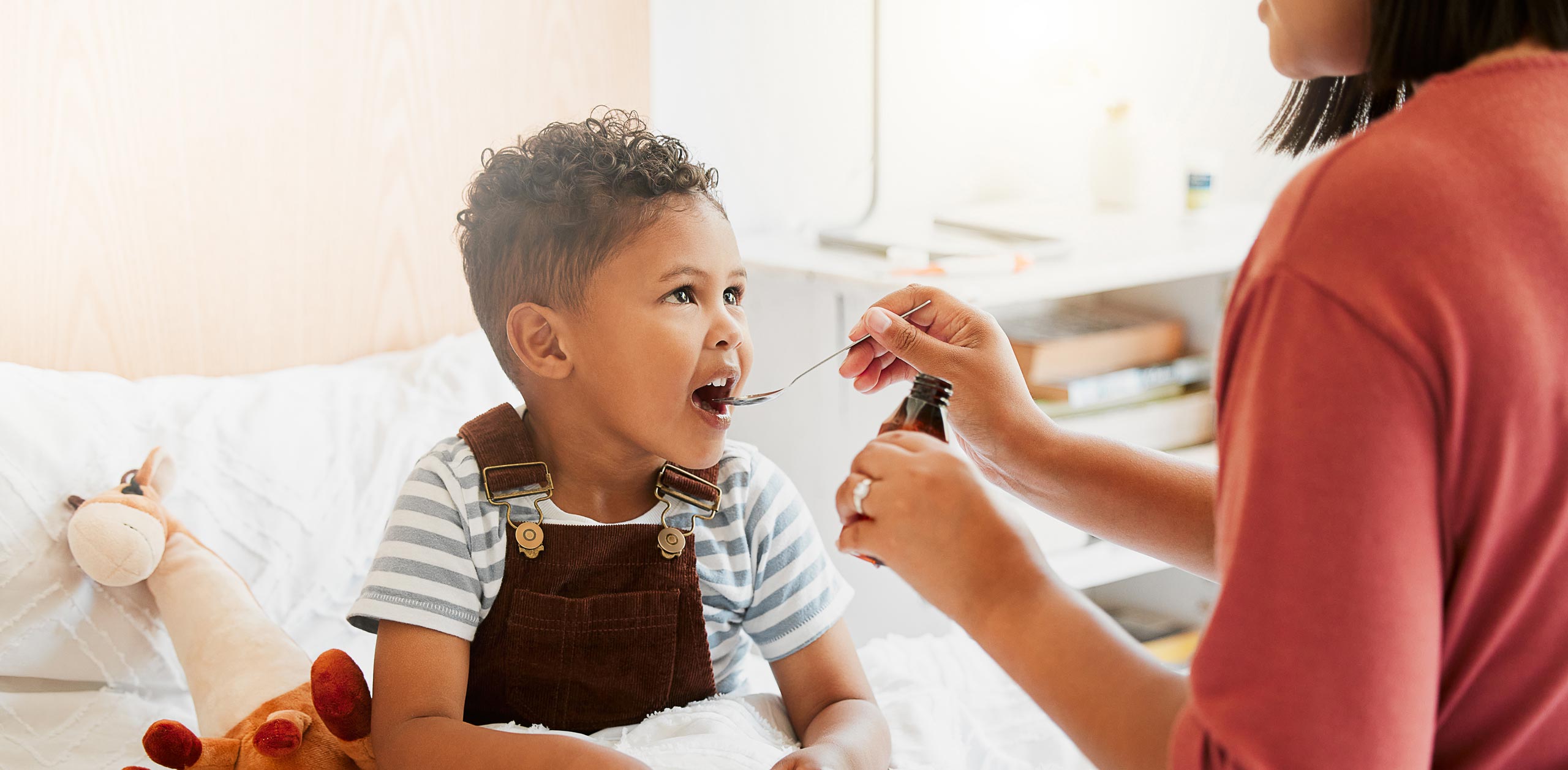 kid gets medicine on a spoon from a parent